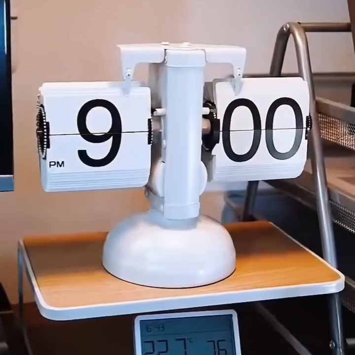 Painted-white round-pedestal PageClock on a desk; real source-video frame